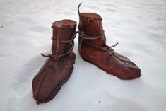 two brown boots sitting on top of snow covered ground