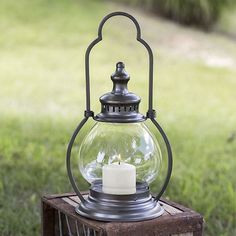 an old fashioned lantern with a lit candle inside on a wooden crate in the grass