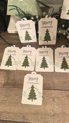 christmas tags with merry trees on them sitting on a wooden floor next to other holiday decorations