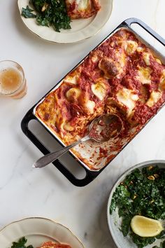 a casserole dish with spinach, cheese and sauce on it next to other dishes