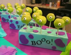 there are many green cake pops with goo eyes on them and the words boo spelled out