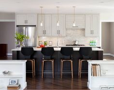 a kitchen with white cabinets and black chairs