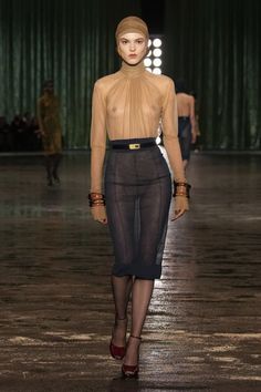 a model walks down the runway in sheer clothing