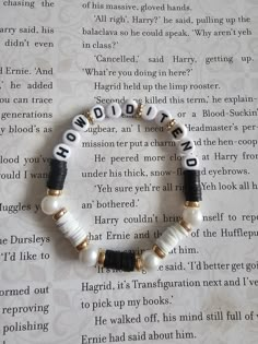 a bracelet with words written on it sitting on top of a piece of paper next to an open book