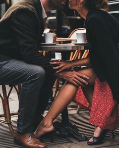 a man and woman sitting at a table with their feet on each other's legs