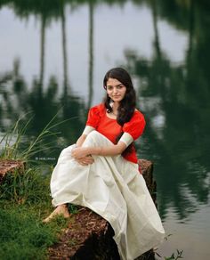 a woman sitting on the edge of a body of water