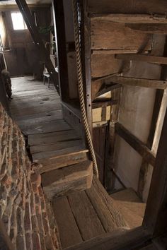 an old wooden porch with rope hanging from it's sides and chairs on the other side