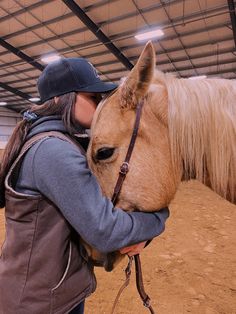 a woman is hugging the head of a horse