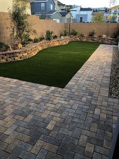 an empty backyard with grass and brick pavers