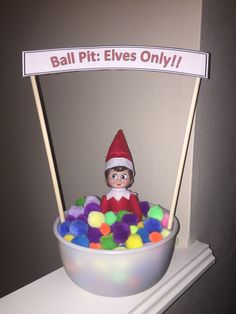 an elf is sitting in a bowl full of candy and has a sign above it that says ball pit elves only