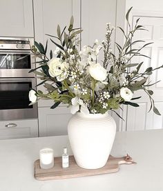 a white vase filled with flowers sitting on top of a counter next to an oven