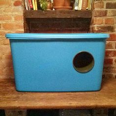 a blue plastic box sitting on top of a wooden shelf next to a brick wall