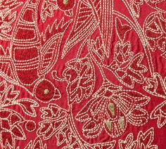 red and white fabric with gold threadwork on the bottom, in front of a flower pattern