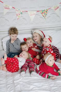 a group of children laying on top of a white bed next to each other in pajamas