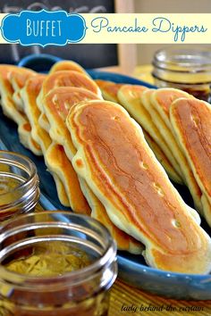 some pancakes are on a blue plate with mustard and seasoning in small bowls next to them