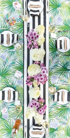 an overhead view of a table with flowers and place settings on it, along with palm leaves