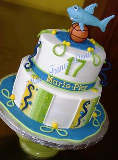 a three tiered cake with a fish and basketball on top, sitting on a table