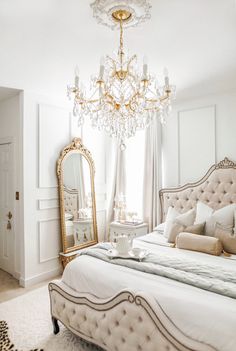 a bedroom with a bed, chandelier and mirror