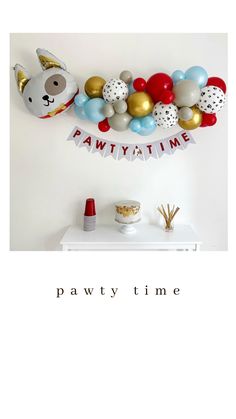 a party time banner hanging on the wall with balloons and other items in front of it