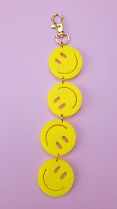 three yellow smiley face key chains on a purple background