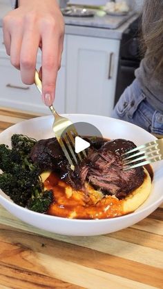 a person holding a fork and knife over a bowl of food with broccoli