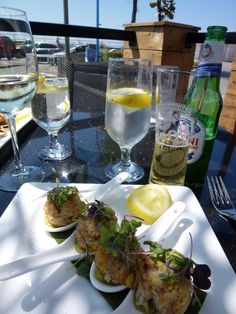 some food is sitting on a white plate with lemons and water in the background