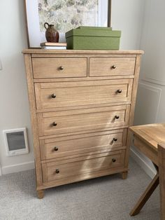 a wooden dresser sitting in a room next to a table with a vase on it