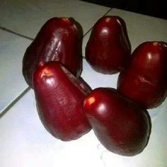 four pieces of fruit sitting on top of a white tile floor