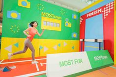 a woman is running in front of a colorful wall with the words most fun on it