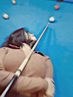 a person is playing pool with balls and a cue in the back ground, as well as an image of a woman's face