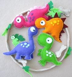 four felt dinosaurs sitting on top of a white circle