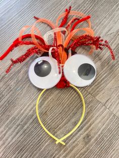 a pair of googly eyes are attached to a headband with orange streamers