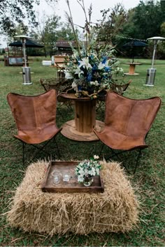 an arrangement of chairs and tables in the middle of a grassy field with hay bales