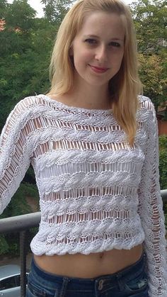 a woman is standing on a balcony with her hands in her pockets and looking at the camera