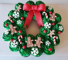 a christmas wreath decorated with green frosting and red ribbon on top of a white plate