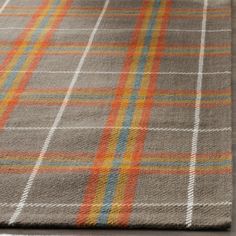 a plaid rug with orange, yellow and blue stripes on the bottom is shown in this image