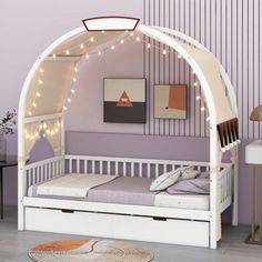 a child's bed with a canopy over it and lights strung from the ceiling