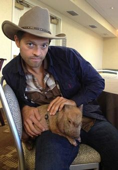 a man in a cowboy hat holding a dog