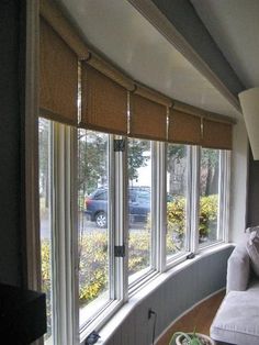 a living room filled with furniture and lots of windows covered in blinds on top of them