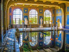 an indoor swimming pool with many windows and statues on the wall, reflecting in it