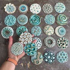 a person is holding several different types of ceramic plates on a table with one hand