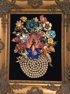 an ornate gold frame holds a bouquet of pearls, brooches and other decorative items