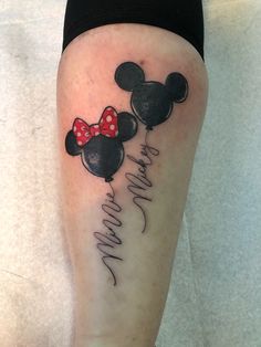 a woman's leg with a mickey and minnie mouse tattoo on it