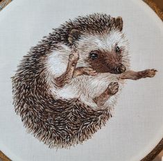 an embroidered hedgehog holding a branch in its paws