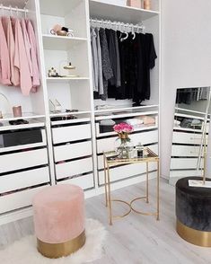 a walk in closet with white shelving and pink velvet foot stools next to it