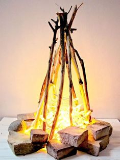 a fire pit made out of sticks and logs on top of a white tablecloth