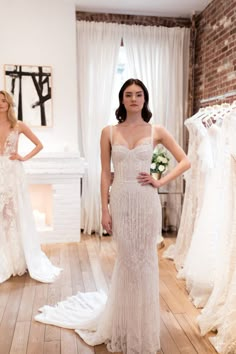 a woman is standing in front of some wedding dresses