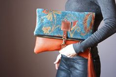 a woman is holding an orange and blue purse