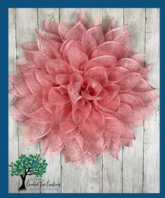 a large pink flower on top of a wooden wall