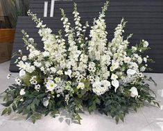 white flowers and greenery are arranged on the floor